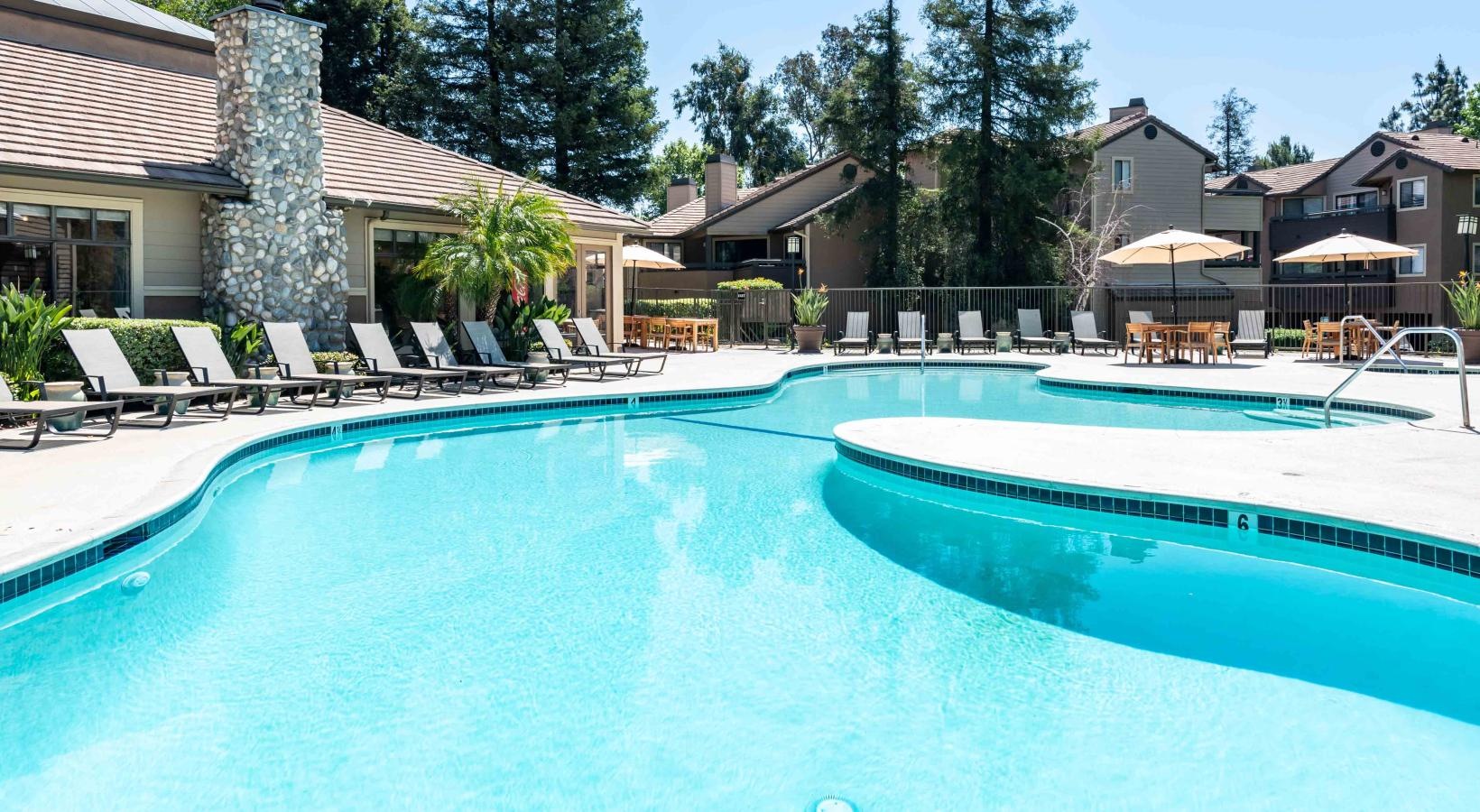 Relax and unwind poolside a swimming pool with chairs and umbrellas next to it